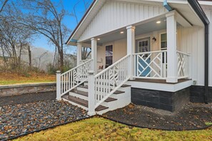 A house with a covered porch, a staircase, and a stone foundation. - Cute Cottage, Central Location, Pet Friendly (Greer)