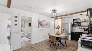 A modern kitchen with a dining area, wooden floors, and a ceiling fan.