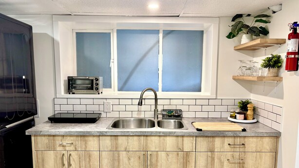 Uma cozinha moderna com micro-ondas embutido, pia dupla e armários de madeira.