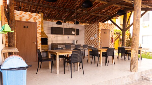 An outdoor patio with a brick wall, a wooden table, and black chairs.
