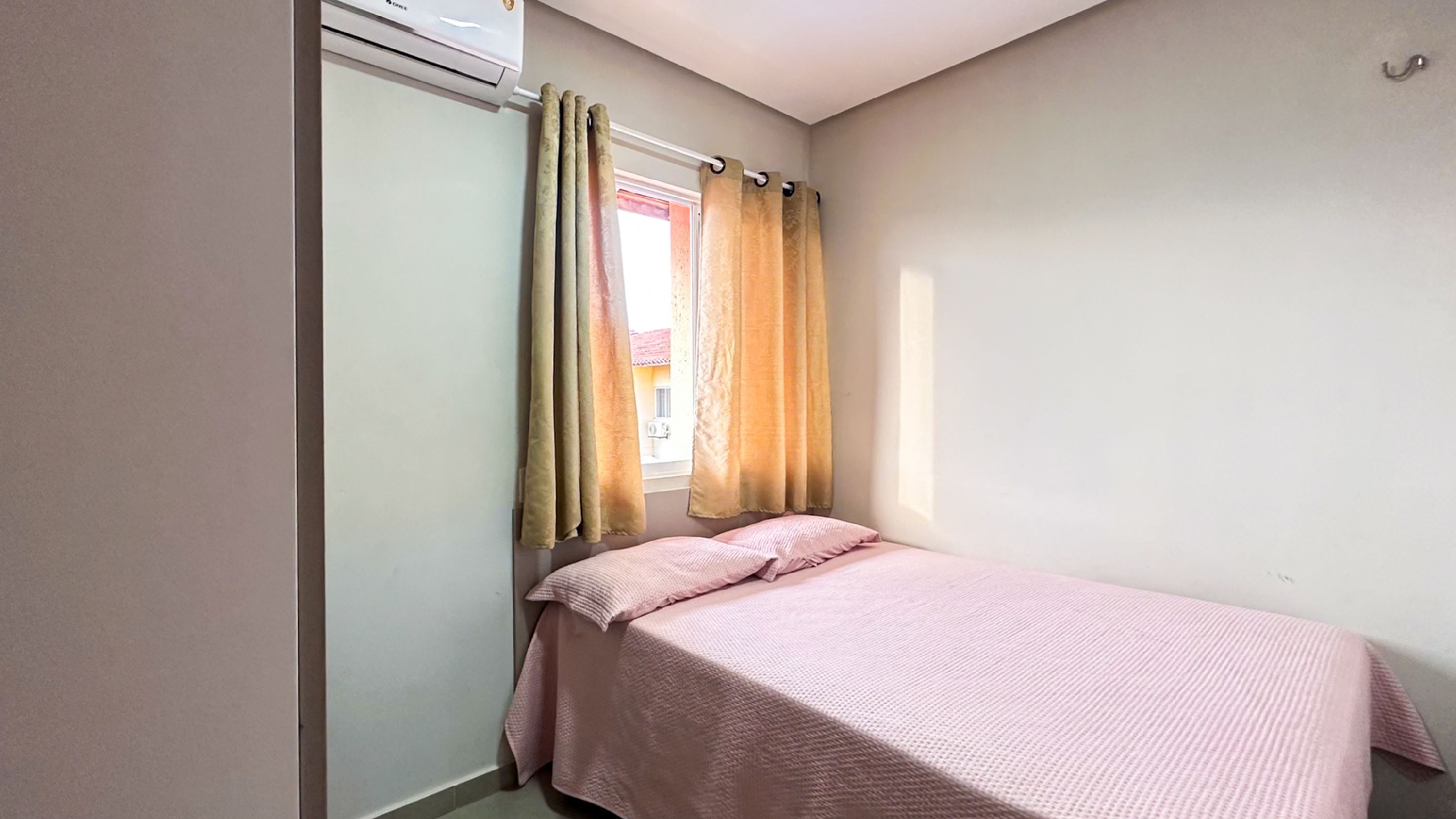Una habitación pequeña con cama individual, ventana, radiador y cortina.