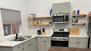 Una cocina moderna con armarios grises, una mesa de comedor de madera y electrodomésticos de acero inoxidable.