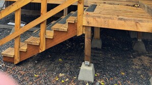 Una cabaña de madera con una escalera de madera que da a una terraza.