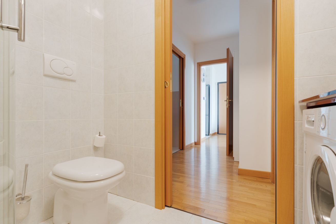 Une salle de bain avec des toilettes, un lave-linge et un plancher en bois.