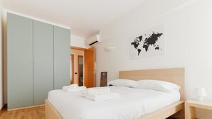 Une chambre à coucher avec un lit, une armoire, une carte du monde accrochée au mur et une porte donnant sur une autre pièce.