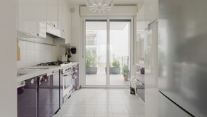 Une cuisine moderne avec des armoires blanches, une cuisinière à gaz et un grand réfrigérateur.