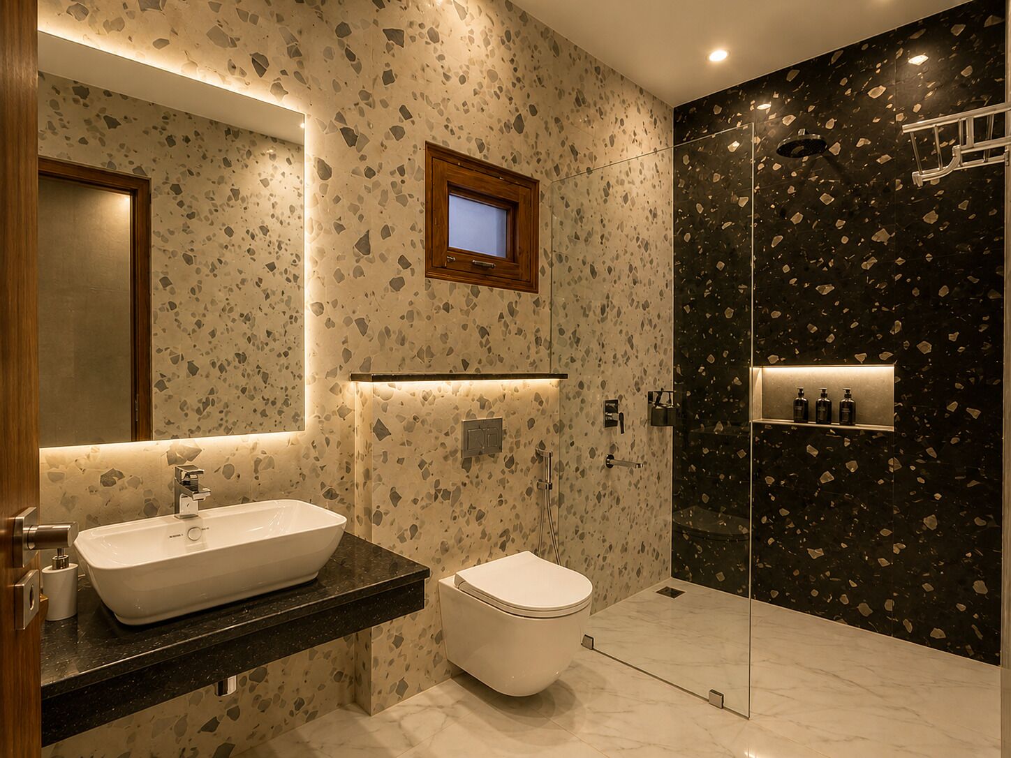 A bathroom with a white sink, a toilet, and a shower area with a dark speckled wall.