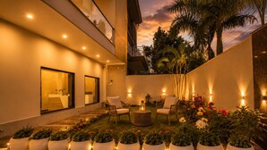 A modern outdoor patio with potted plants, seating, and ambient lighting. - Tamarind Leaf Residency Noida Sector 50 Metro & Spectrum Mall (Noida)