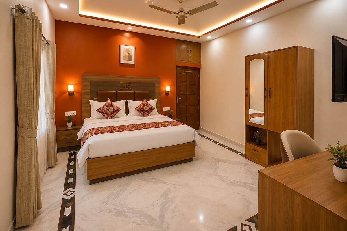 A hotel room with a bed, bedside tables, a desk, a wardrobe, a ceiling fan, and a wall-mounted TV.