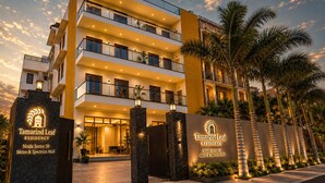 A multi-story residential building with balconies, a gated entrance, and palm trees. - Tamarind Leaf Residency Noida Sector 50 Metro & Spectrum Mall (Noida)