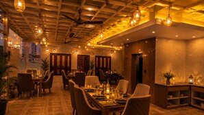 A restaurant with a long dining table, multiple chairs, ceiling fans, and hanging light fixtures. - Tamarind Leaf Residency Noida Sector 50 Metro & Spectrum Mall (Noida)