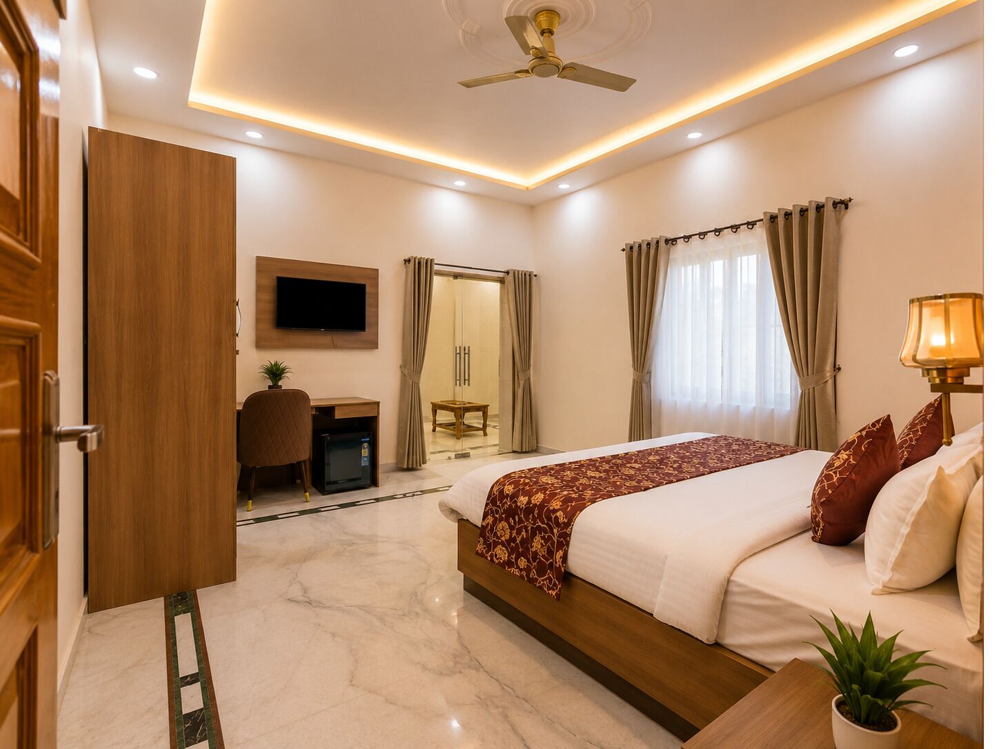 A hotel room with a bed, a desk, a chair, a TV, a ceiling fan, and a window with curtains.