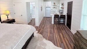 A bedroom with a bed, a wooden ceiling fan, and a white door leading to a bathroom. - Private Hilltop Estate Near Round Top - Main House, Guest House & Barn (Fayetteville)