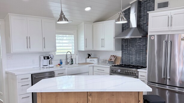 A modern kitchen with white cabinets, a large island with stools, stainless steel appliances, and pendant lighting. - Private Hilltop Estate Near Round Top - Main House, Guest House & Barn (Fayetteville)
