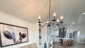 A dining area with a long table, chairs, a chandelier, a Christmas tree, and a sofa with a patterned cushion. - Private Hilltop Estate Near Round Top - Main House, Guest House & Barn (Fayetteville)
