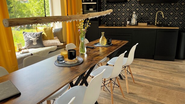 A modern kitchen with a wooden table, white chairs, and a view of greenery outside. - Bavaria Mountain Ski Lodge Dog Pool terrace grill (Lohberg)