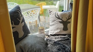 A cozy seating area with a view of a green landscape, a table with chairs, and decorative pillows. - Bavaria Mountain Ski Lodge Dog Pool terrace grill (Lohberg)