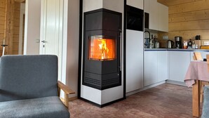 Eine moderne Küche mit Kaminofen, weißen Schränken und einem Essbereich mit Tisch und Stühlen.