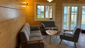 Ein gemütliches Zimmer mit Holzwänden, einem Sofa, einem Tisch und zwei Stühlen.
