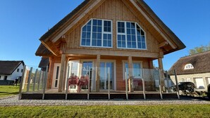 Ein Gebäude aus Holz mit großen Fenstern und einem Strohdach.
