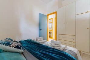 Makuuhuoneessa on sänky, vaatekaappi ja kylpyhuone, joka näkyy avoimesta ovesta.