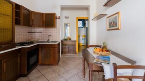Una cucina con mobili in legno, un fornello e un tavolo da pranzo con sedie.