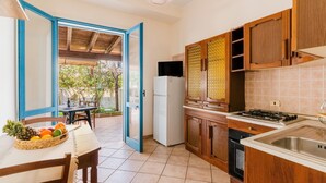 Una cucina con mobili in legno, piano cottura a gas, frigorifero e zona pranzo con tavolo e sedie.