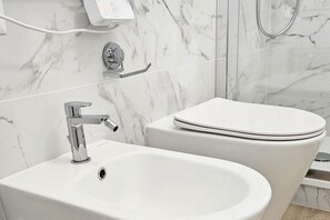 Un baño con lavamanos blanco, inodoro y zona de ducha.