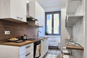 A modern kitchen with wooden countertops, a built-in oven, a window with a view, and a small dining area with stools. - Duomo at 8 min - Downtown, Qc Terme, 2 roomsDuomo at 8 min - Downtown, Qc Terme, 2 ca (Milan)