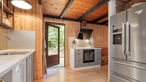 Una cocina moderna con paredes de madera, un refrigerador de acero inoxidable y un horno empotrado.