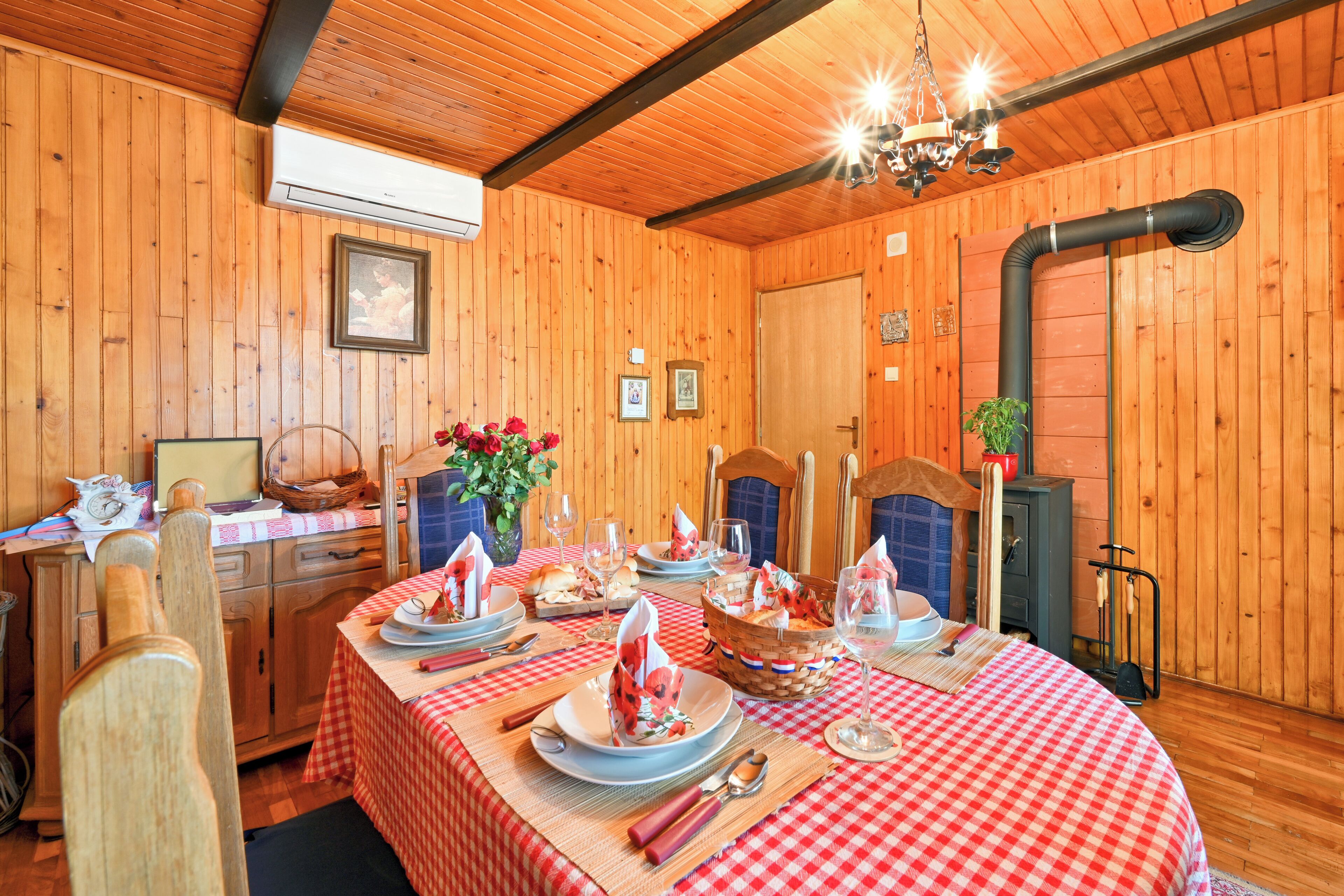 Een houten interieur met een voor vier personen gedekte eettafel, een open haard en een kroonluchter.