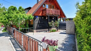 Una casa de madera con techo rojo, un balcón y un camino de entrada de grava.