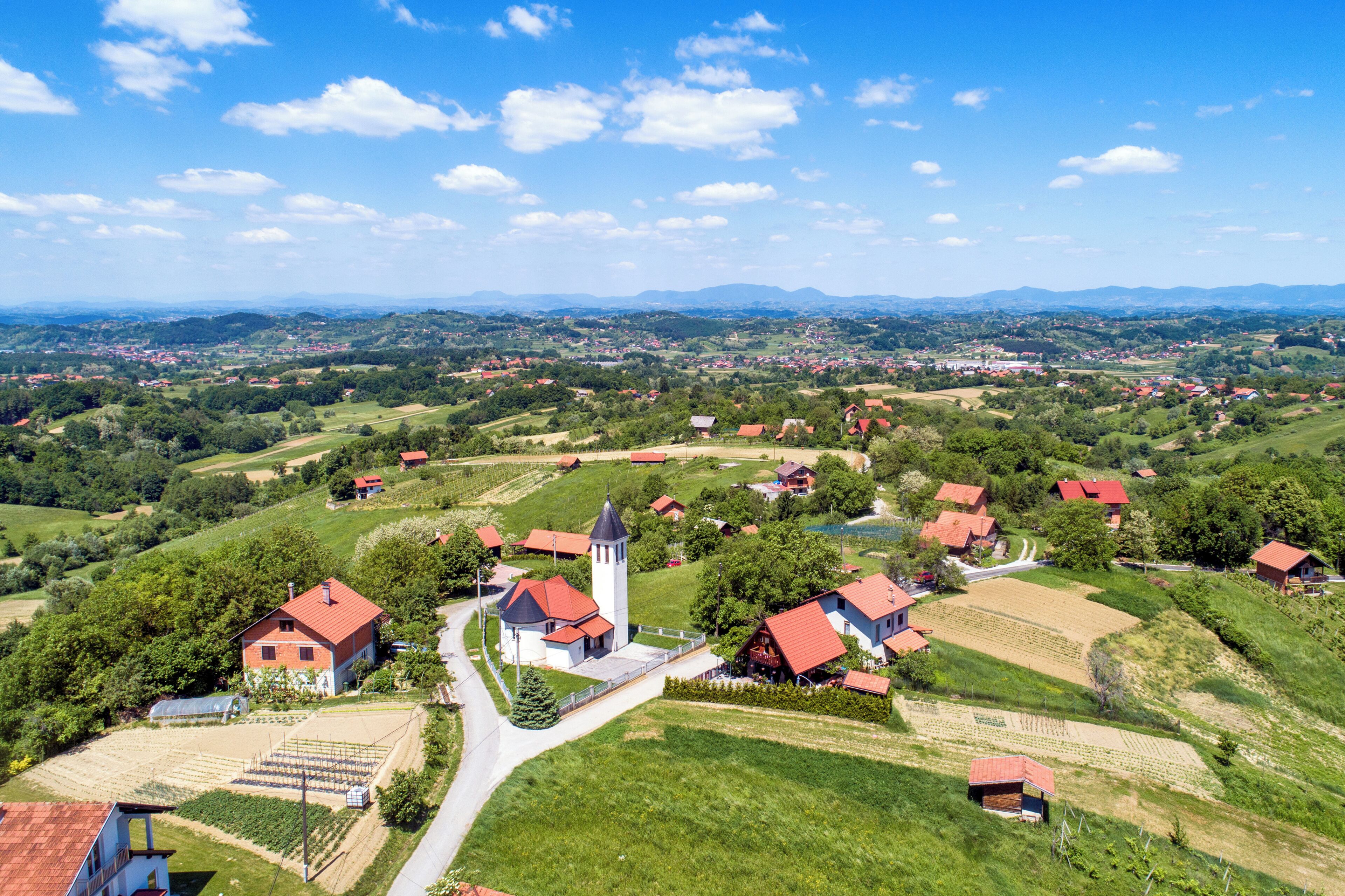 A rural landscape with houses, a church, and fields.