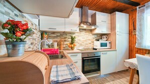 Una cocina compacta con encimera de madera, un lavabo, un microondas y una estufa.