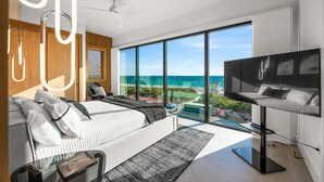 A modern bedroom with a large bed, a TV, and a view of the ocean. - Dream State ~ Gulf Front/Across from Beach! (Bradenton Beach)