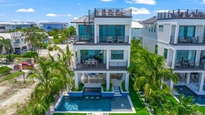 Un immeuble résidentiel moderne à plusieurs étages, doté d’une piscine et entouré de palmiers et d’autres plantes.