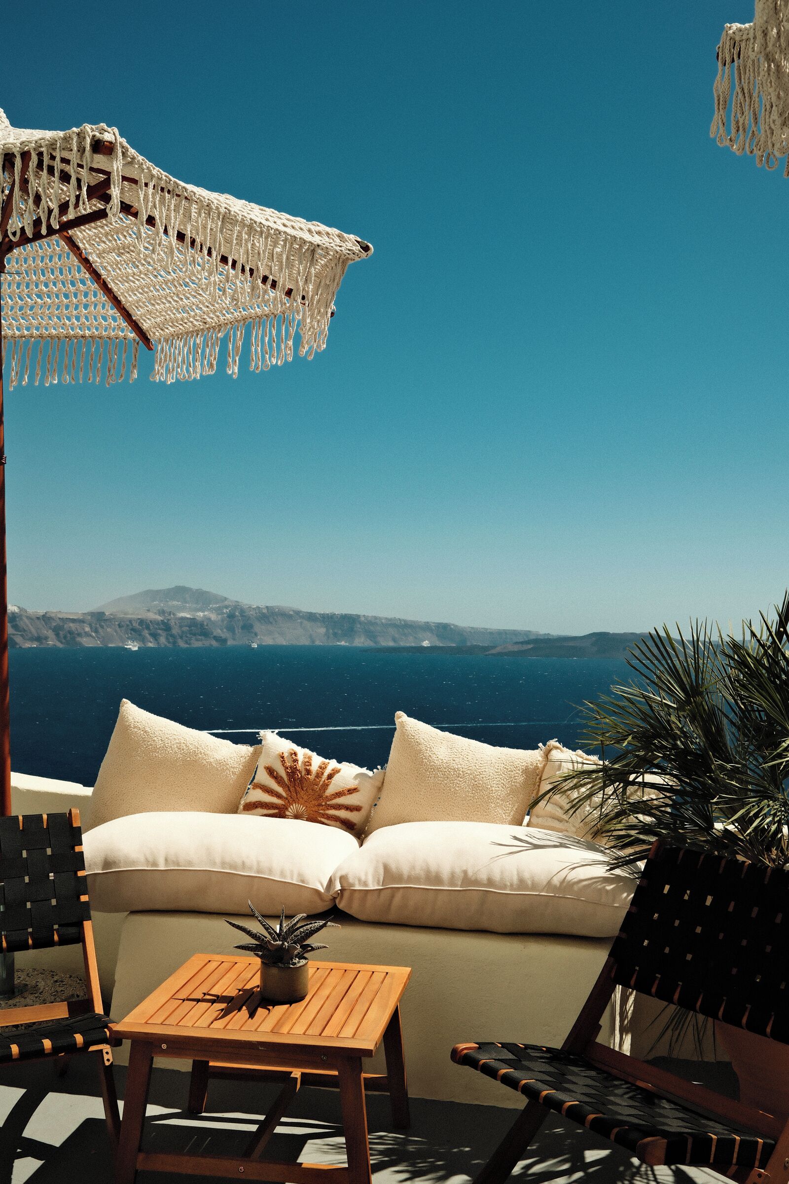 A cozy outdoor seating area with a view of the sea and distant hills.