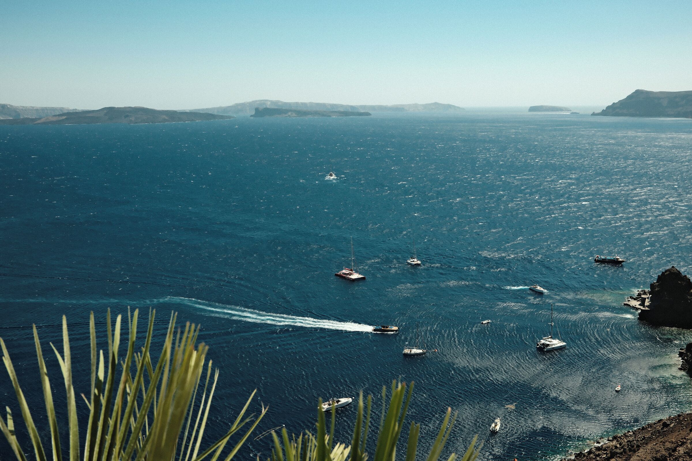 A coastal view with boats on the water and a rocky shoreline.