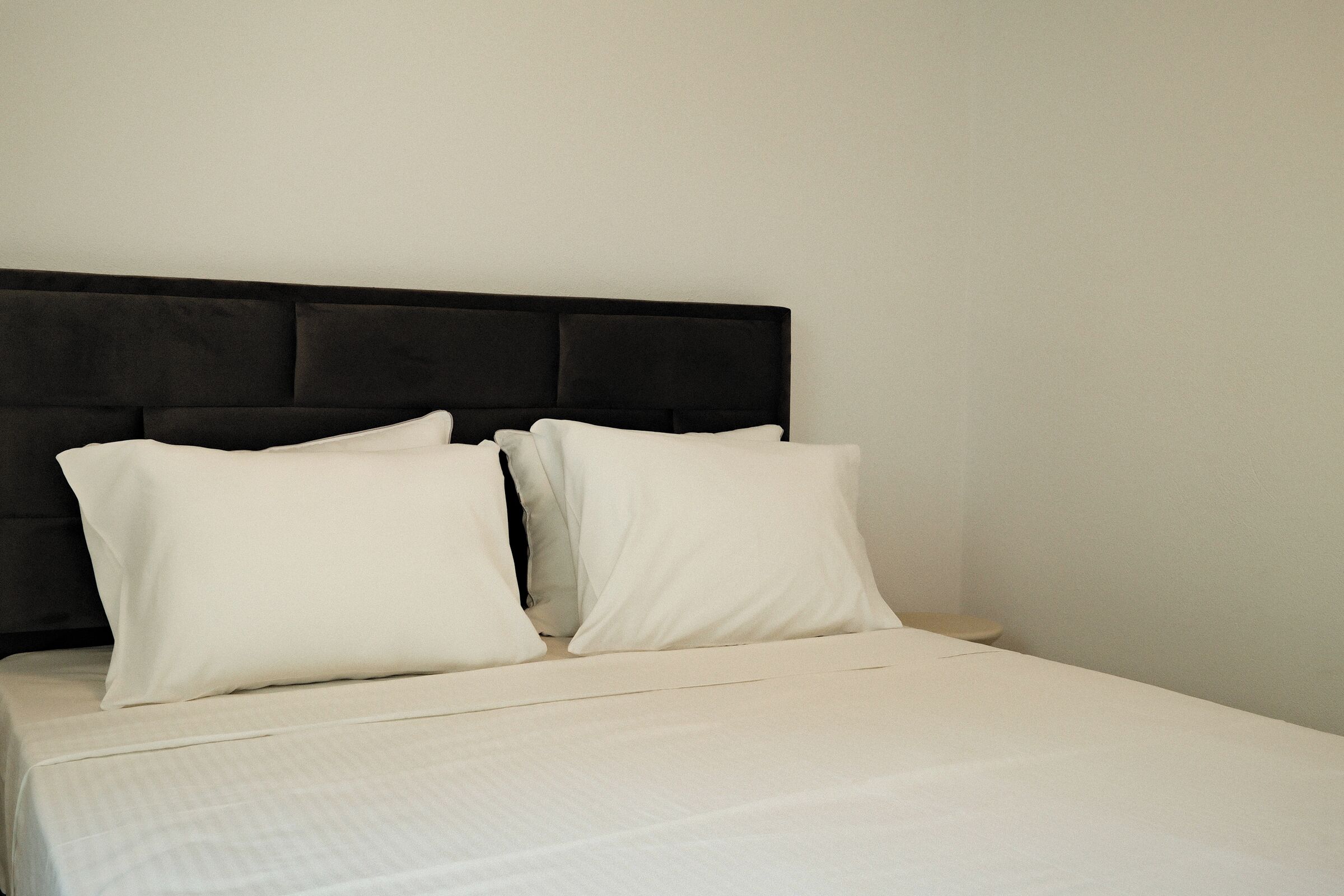 A bed with a black headboard and white bedding in a hotel room.