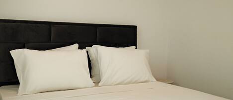 A bed with a black headboard and white bedding in a hotel room.