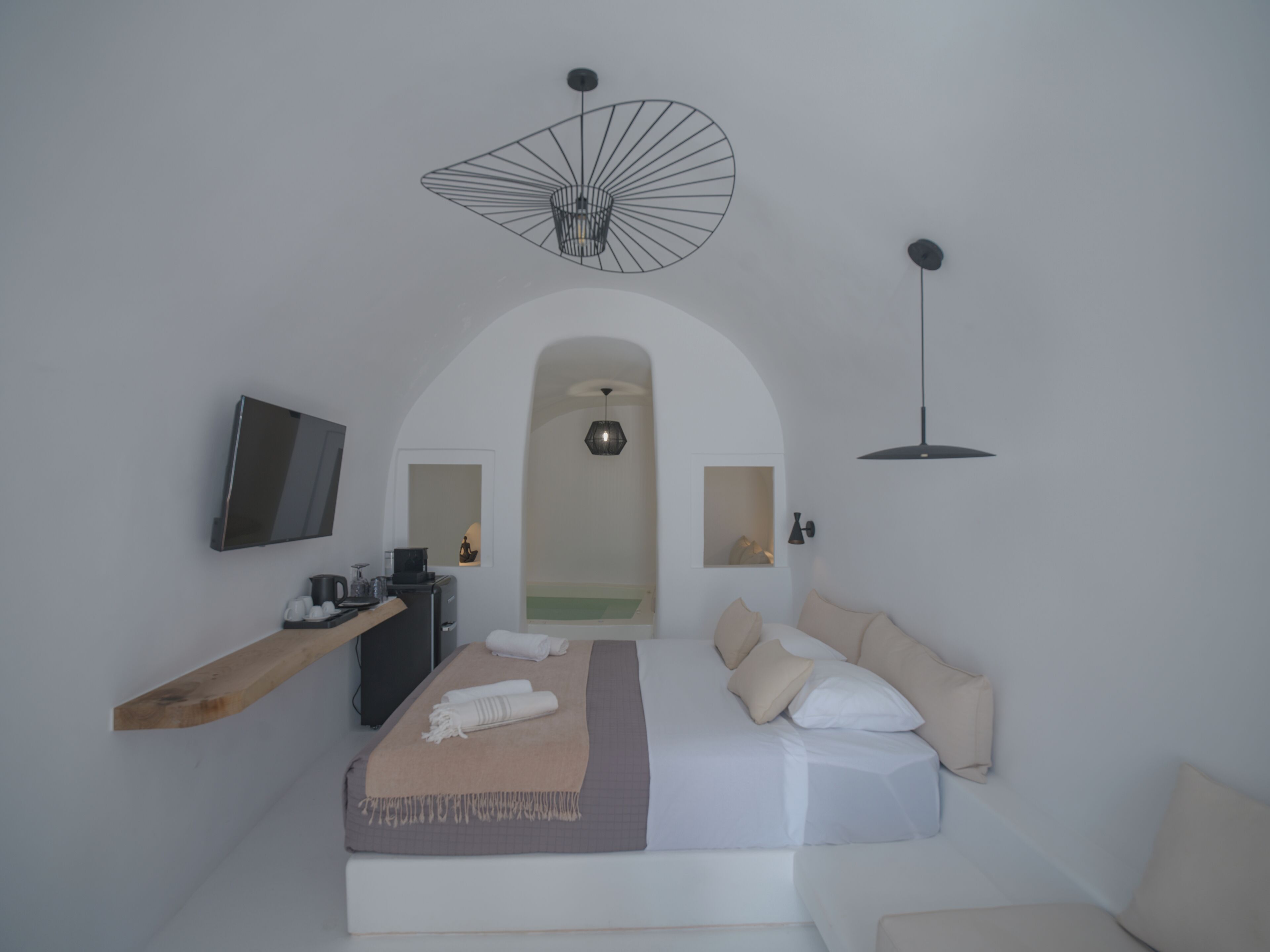 Un dormitorio moderno con cama, televisor, escritorio y una lámpara de techo original.
