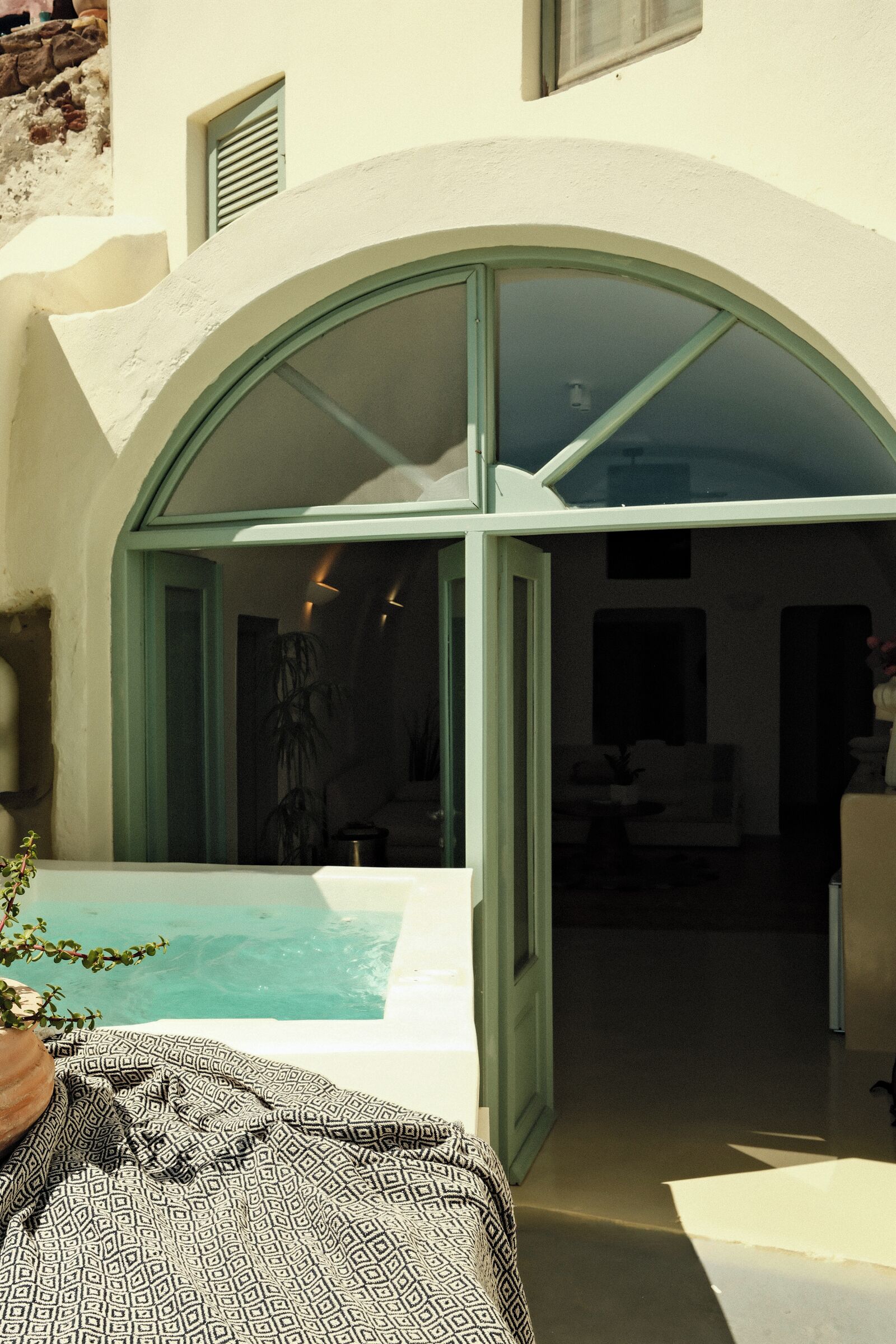 A modern villa with a pool, an open archway leading to a living area, and a potted plant.