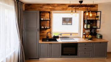 A kitchen with a built-in dishwasher, a window with a view, and a shelf with kitchenware.