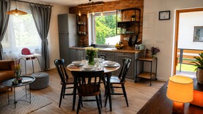 Una cocina moderna con comedor, suelo de madera y vistas a zonas verdes.
