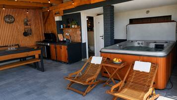 A cozy outdoor seating area with wooden loungers and a hot tub.