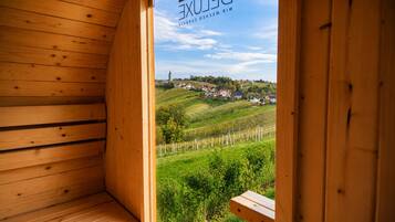 A wooden interior with a view of a rural landscape, including houses and vineyards.