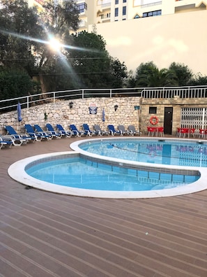 A swimming pool with lounge chairs and a stone wall. - Apartment 'T1 Superior' with Shared Pool, Wi-Fi and Air Conditioning (Portimão)