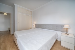 A bedroom with a bed, nightstands, a lamp, a wardrobe, and a door. - Apartment 'T1 Superior' with Shared Pool, Wi-Fi and Air Conditioning (Portimão)