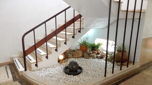 A staircase with a wooden handrail, white walls, and a small garden area with rocks and potted plants. - Apartment 'T2 Premium' with Shared Pool, Wi-Fi and Air Conditioning (Portimão)