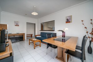 Una sala de estar moderna con una mesa de comedor, sofá y televisor.
